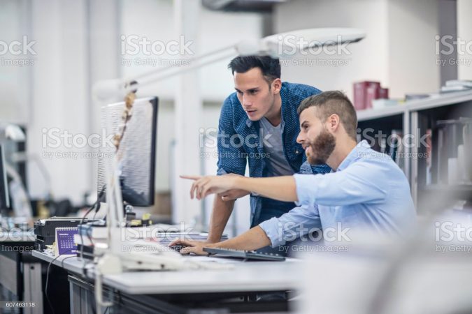 Industrial designers at the office discussing project on the computer.